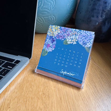 Small calendar on a desk next to a laptop