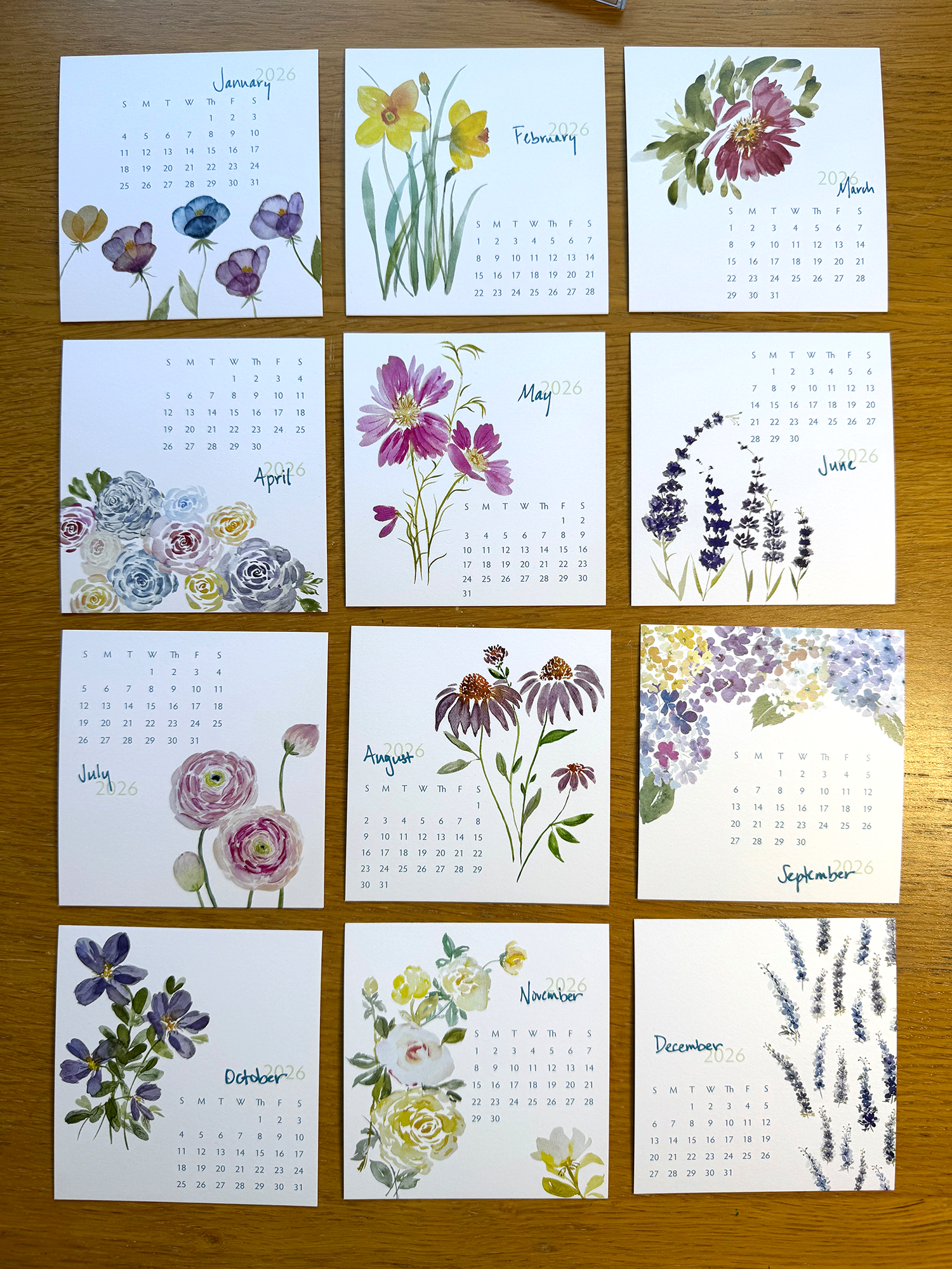 Calendar with floral designs for each month on a wooden surface