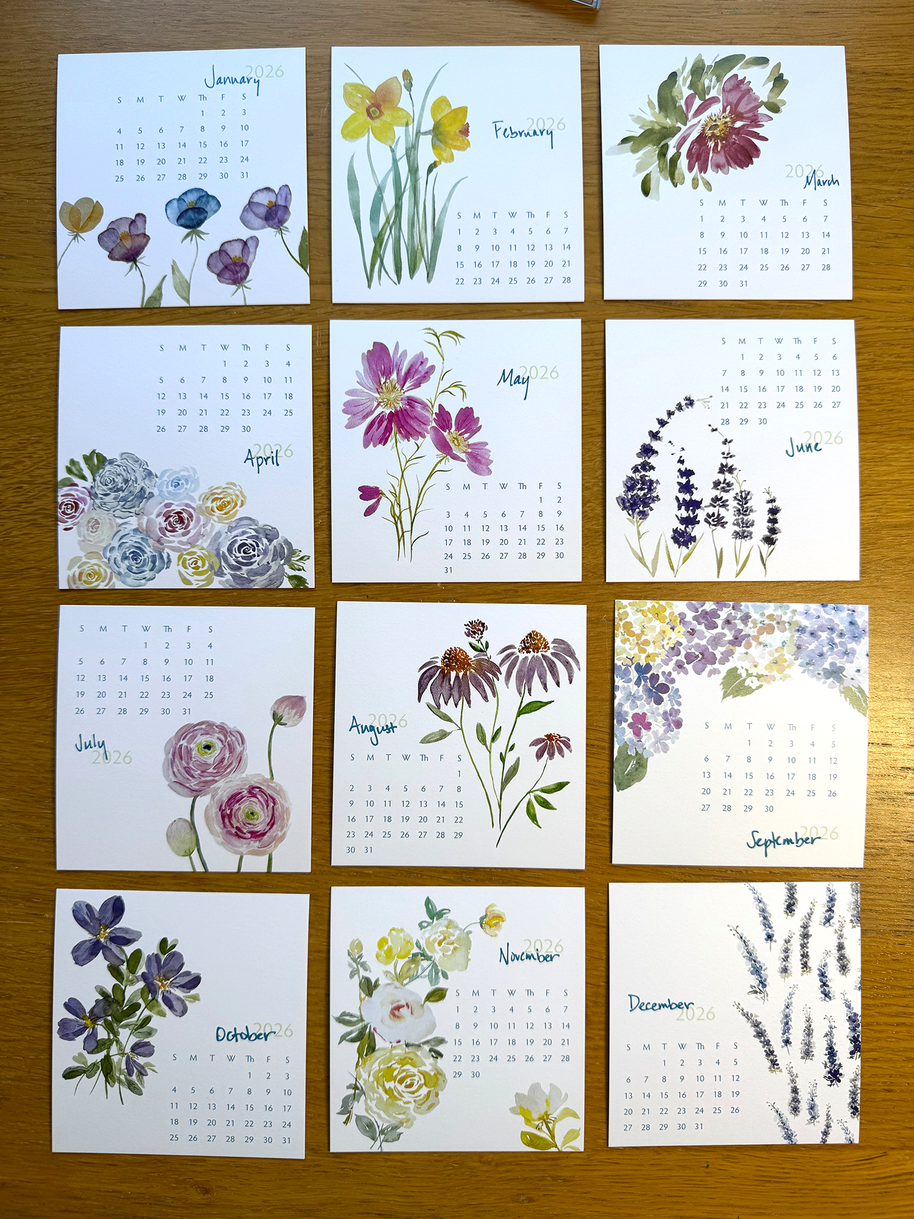 Calendar with floral designs for each month on a wooden surface
