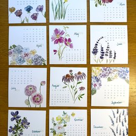 Calendar with floral designs for each month on a wooden surface