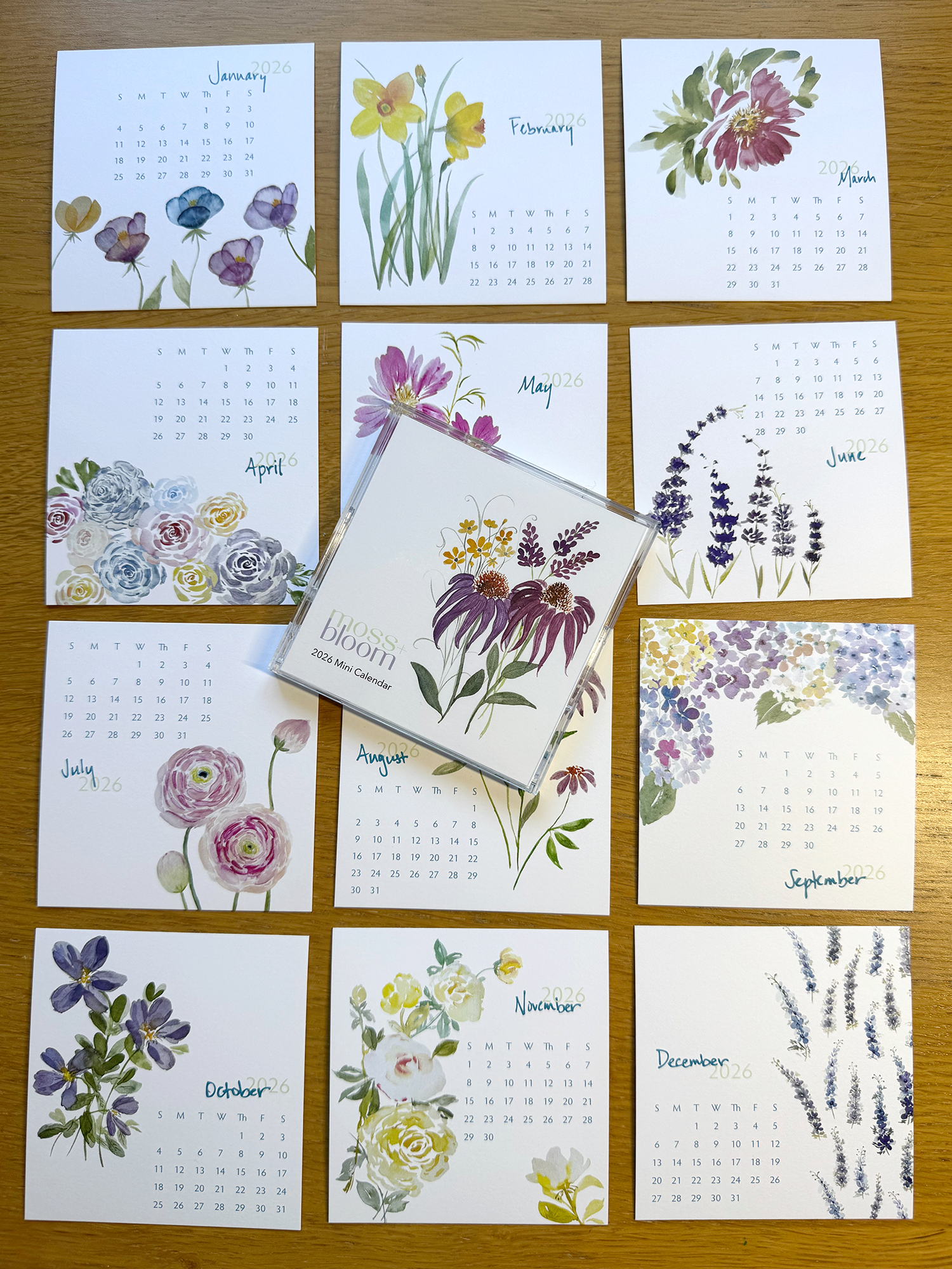 Set of twelve floral calendars on a wooden surface
