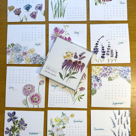 Set of twelve floral calendars on a wooden surface