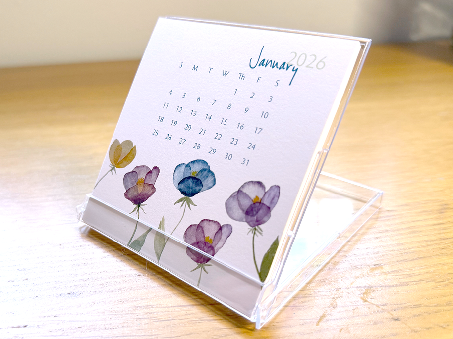 Mini desk calendar with floral design on a wooden surface