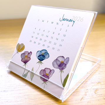 Mini desk calendar with floral design on a wooden surface