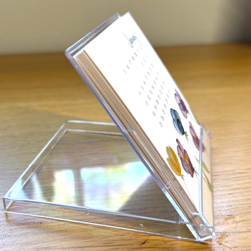 Acrylic stand holding a mini desk calendar on a wooden surface