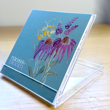 A colorful mini desk calendar with floral design on a stand on a wooden desk