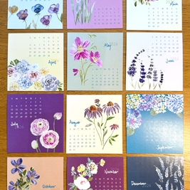 Calendar with floral designs for each month on a wooden surface