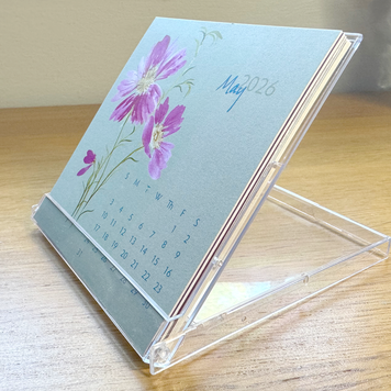 Small calendar with floral design on a stand, placed on a wooden surface.