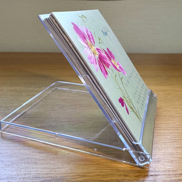 Clear acrylic card holder with floral design on a wooden surface