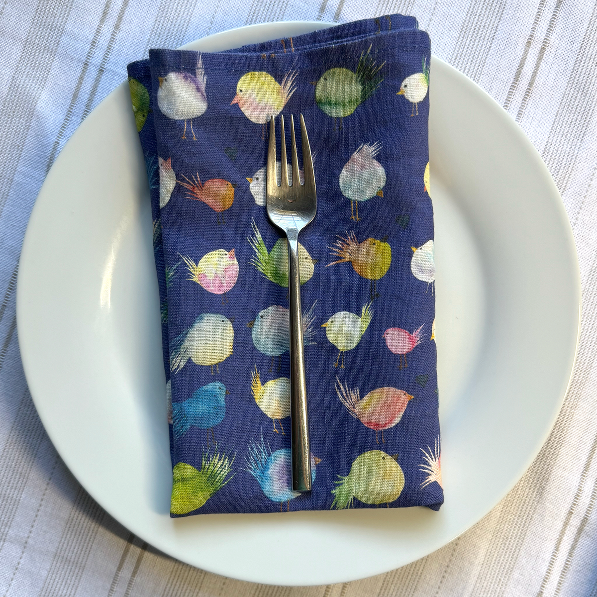 Napkin with colorful bird pattern on a white plate with a fork