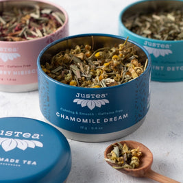 Justea tea tins with chamomile dream tea on a light surface